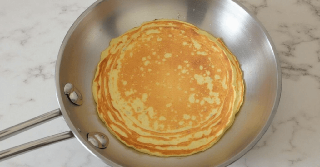 Fluffige Pfannkuchen ohne Ei, serviert mit frischen Früchten und einem Schuss Ahornsirup.